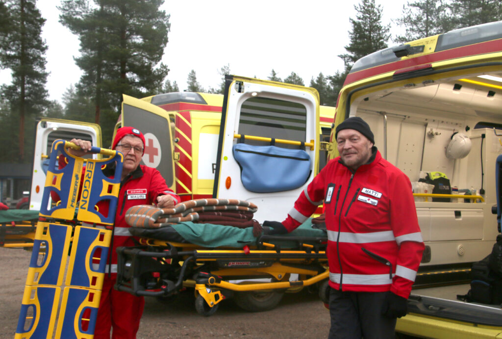 Ambulanssit ovat päivystäjien työkalupakki, jossa he voivat hoitaa potilaita ja olla itse säältä suojassa lämpimässä. Mauri Koivusalo ja Matti Mustajärvi esittelevät kuvassa ambulanssin varusteita: sähköpaareja ja rankalautaa.